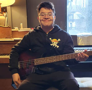 Picture of our guitar and bass guitar student holding a bass by the window after jamming to some Green Day songs during his guitar lesson. 